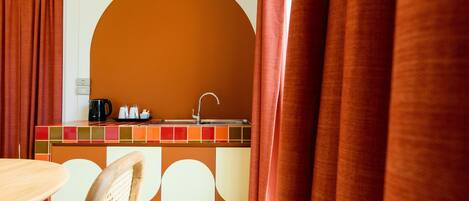 A kitchen area with a sink, a coffee maker, and a kettle on the counter.