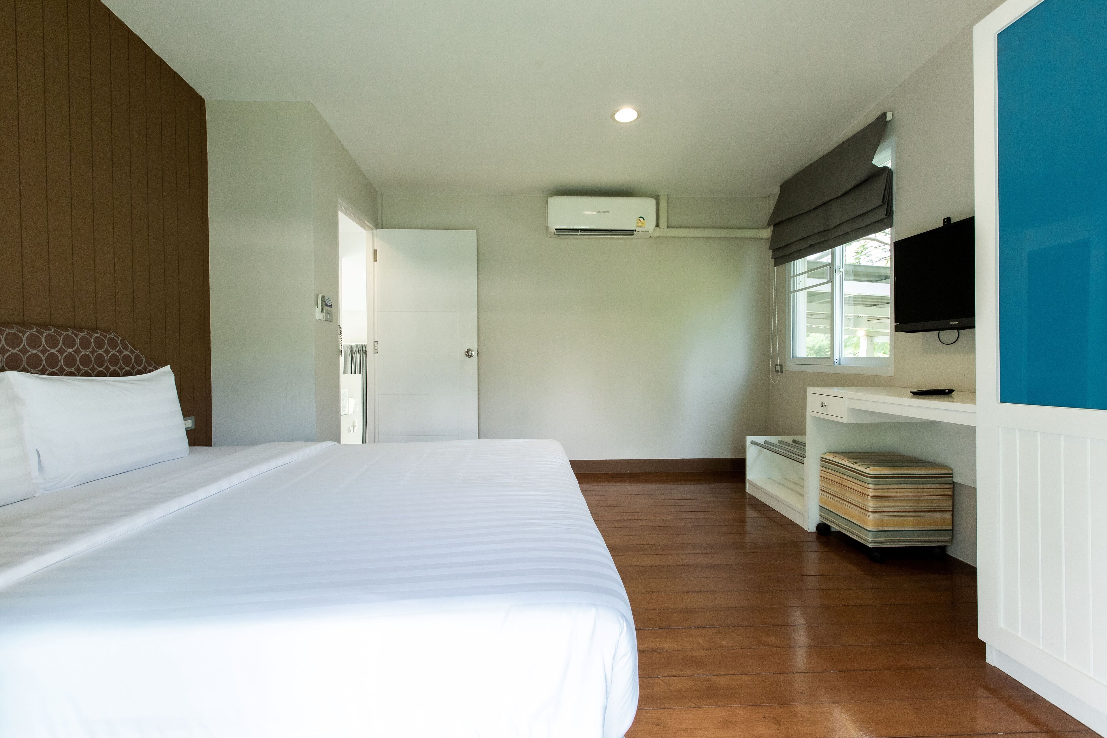 Un dormitorio con cama, escritorio, televisión y equipo de aire acondicionado.