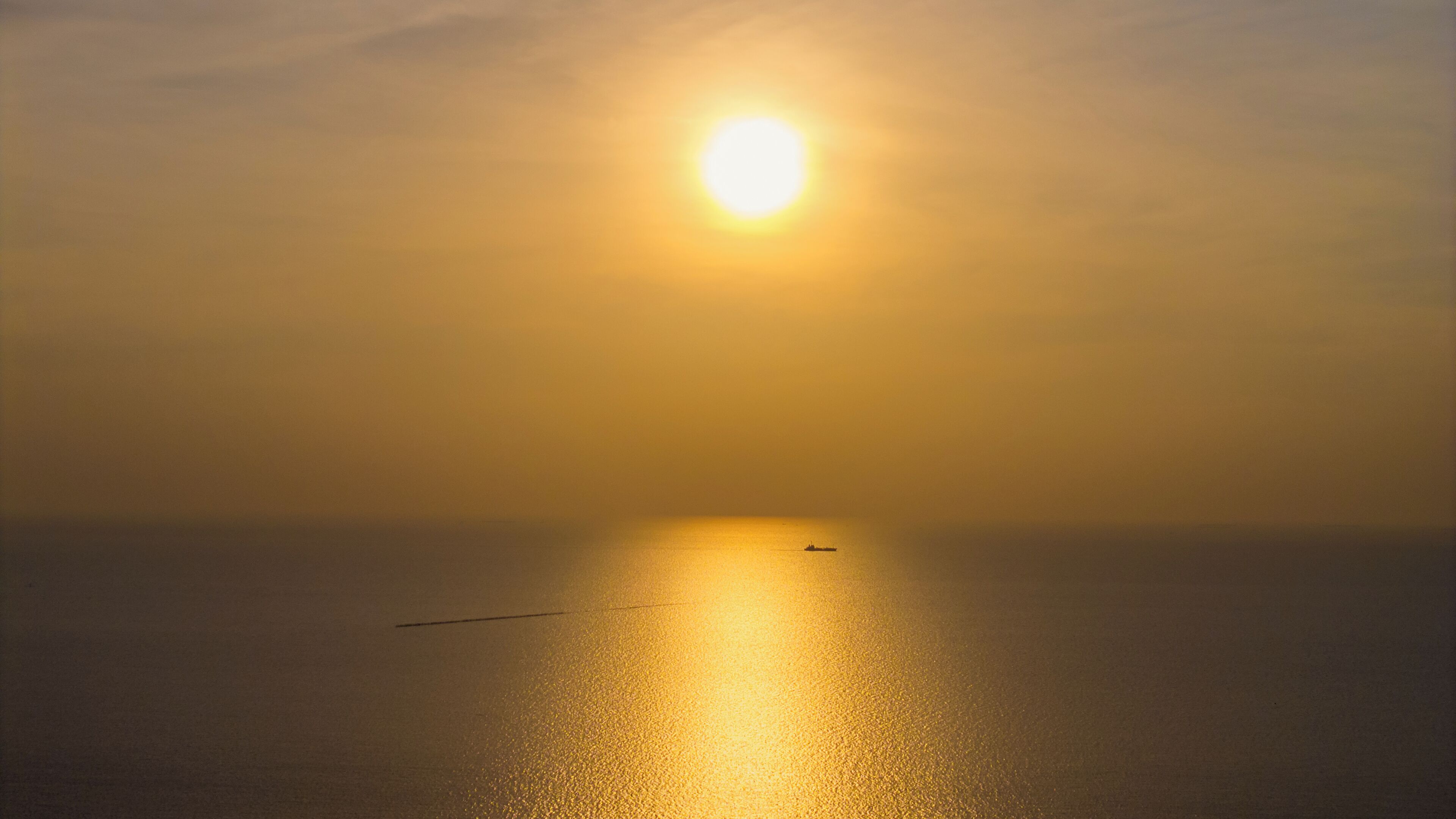 Mar calma com um barco e céu claro.
