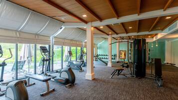 Een fitnessruimte met cardioapparatuur, krachttoestellen en een spiegelwand.