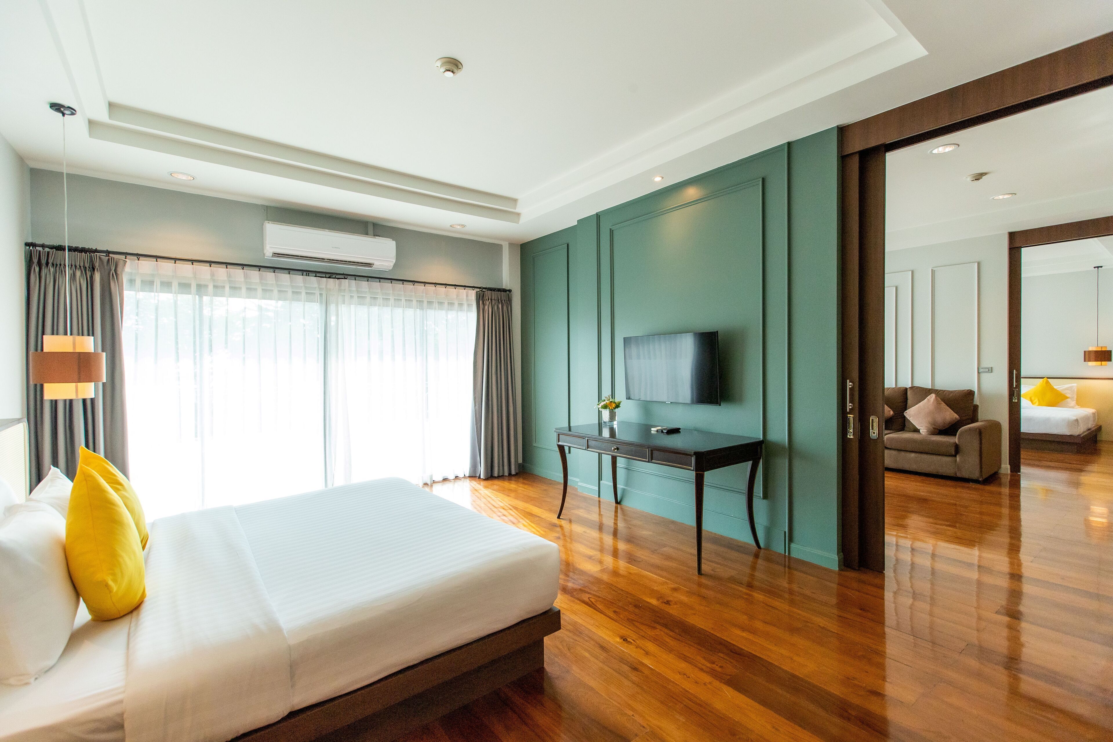 Una habitación de hotel moderna con una cama grande, un escritorio con televisor de pantalla plana y vistas al área de estar contigua.