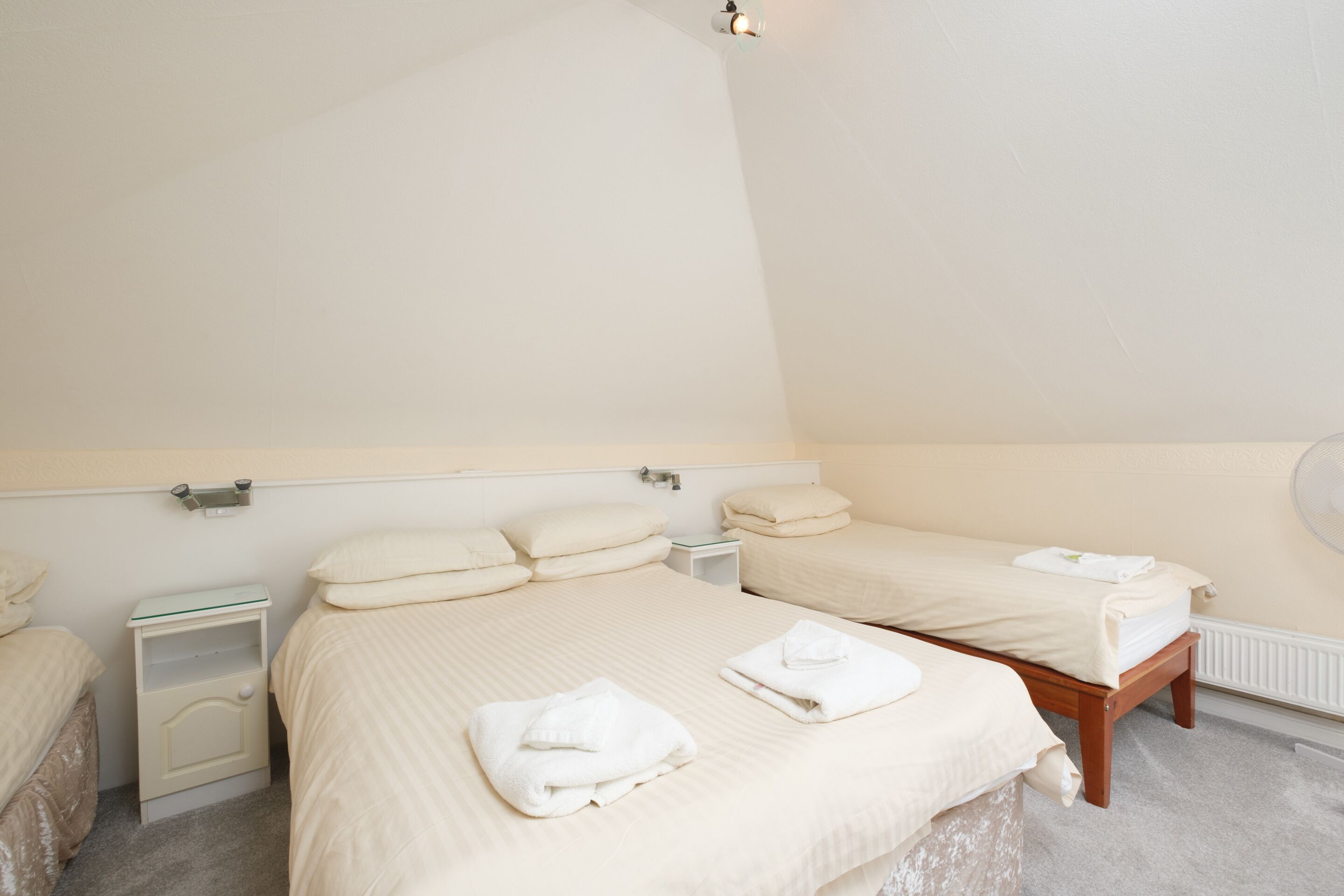A hotel room with two single beds, each with a bedside table and a lamp.