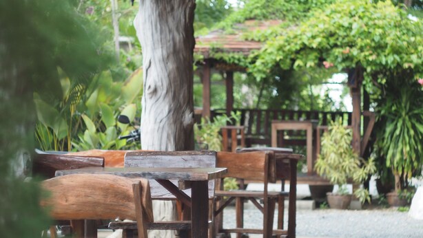 A wooden bench and table set in an outdoor area with a pergola and potted plants. - Phutawan Kan Resort (Kanchanaburi)