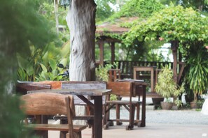 A wooden bench and table set in an outdoor area with a pergola and potted plants. - Phutawan Kan Resort (Kanchanaburi)