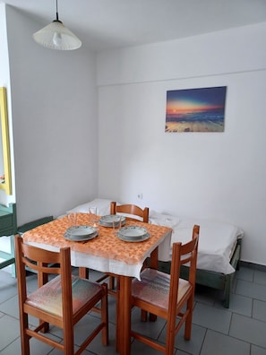 Un comedor con una mesa dispuesta para cuatro, sillas, una lámpara colgante y un cuadro en la pared.