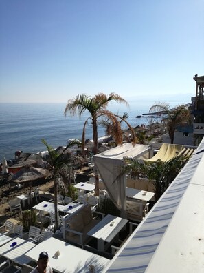 Ein Resort am Strand mit Außenbestuhlung, Palmen und Meerblick.