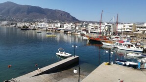 A marina with boats docked, a clear sky, and a mountainous backdrop. - Olympic Star Apartments (Hersonissos)