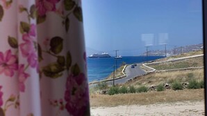 Una carretera costera con un barco a lo lejos y un paisaje urbano al fondo.