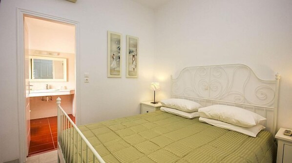 A bedroom with a bed, a nightstand, a lamp, and a wall-mounted painting.