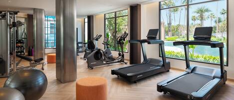 A modern gym with cardio machines, weight equipment, and a view of the outdoors.