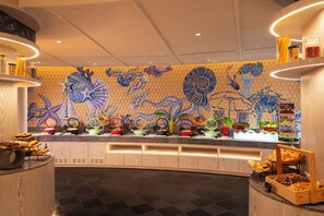 A buffet with various dishes and a decorative wall with marine life illustrations. -  Amari Bangsaen (Chonburi)
