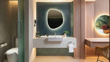 A modern bathroom with a freestanding toilet, a sink with a mirror above it, and a wooden vanity with a plant.
