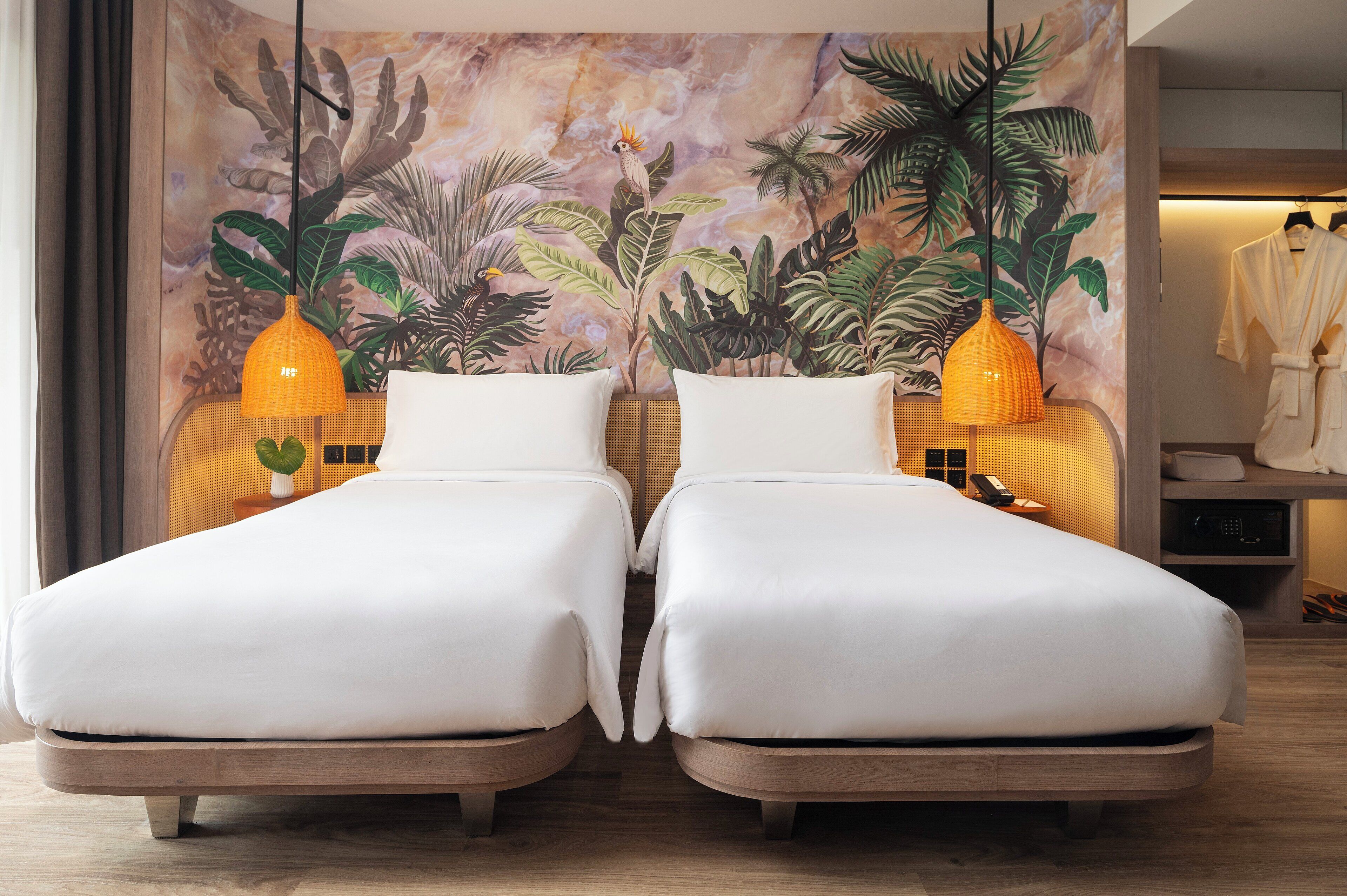 Habitación con dos camas, un mural tropical y un perchero para bata.