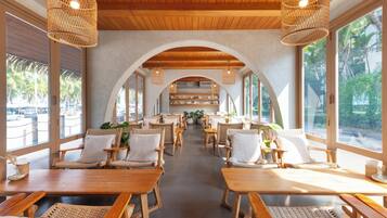 A spacious indoor area with wooden tables and chairs, large windows, and a central archway.