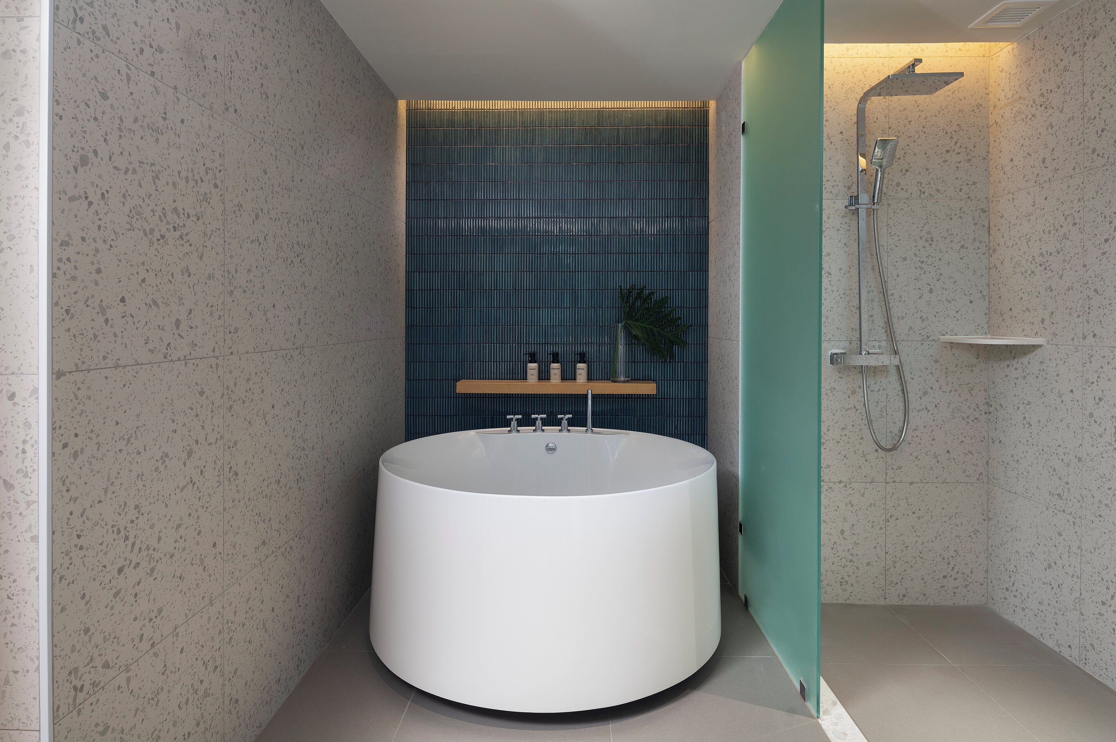 Ein modernes Badezimmer mit einer freistehenden Badewanne, einer Duschkabine und einem Ablagebereich für Pflegeprodukte.