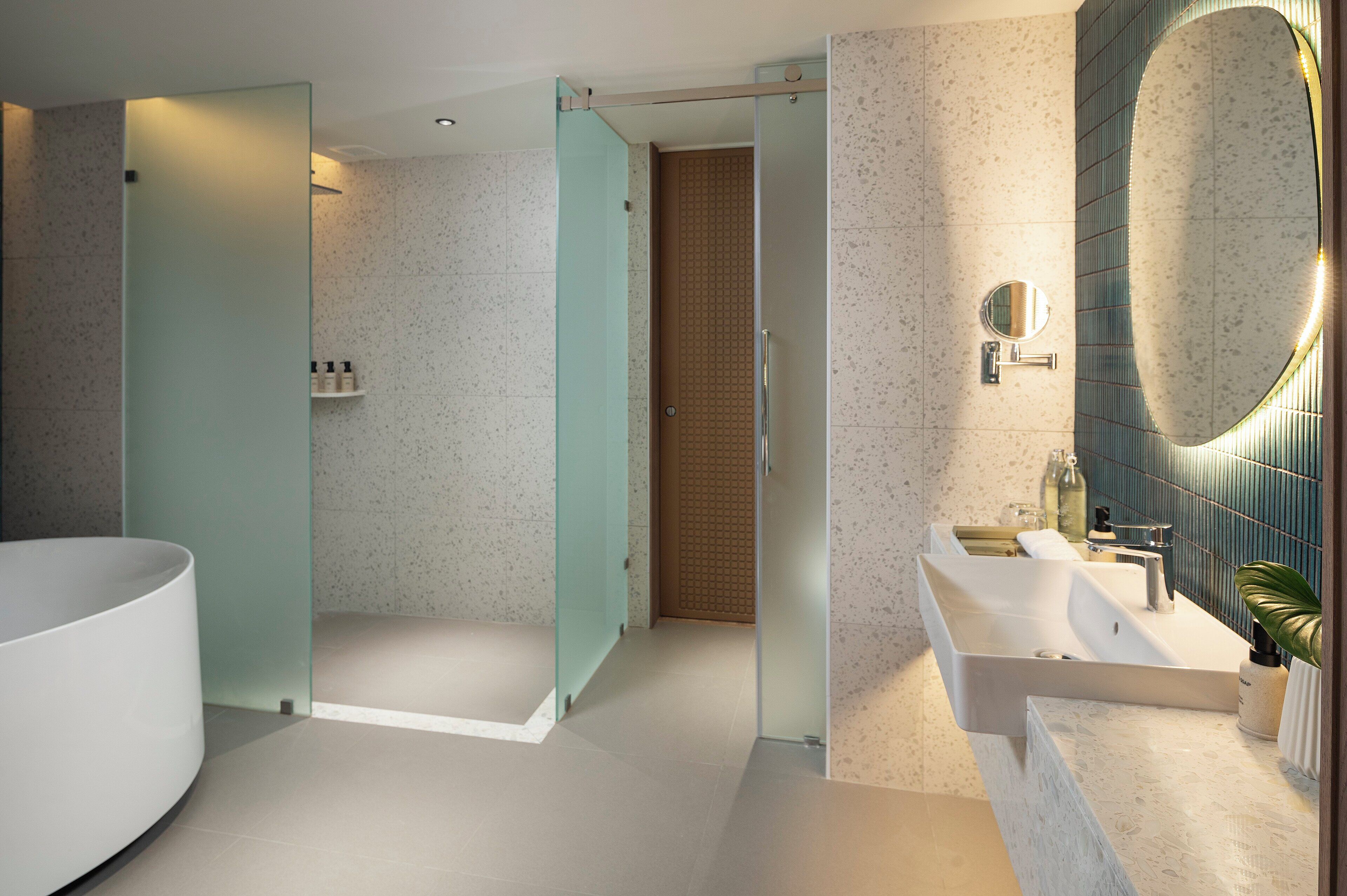 Une salle de bain moderne avec une grande baignoire blanche, une douche à parois de verre et un meuble-lavabo avec un miroir.