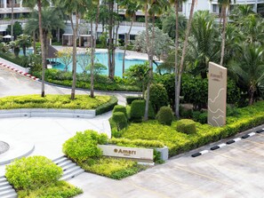 A landscaped area with a pool, palm trees, and a sign for 'Amari'. -  Amari Bangsaen (Chonburi)