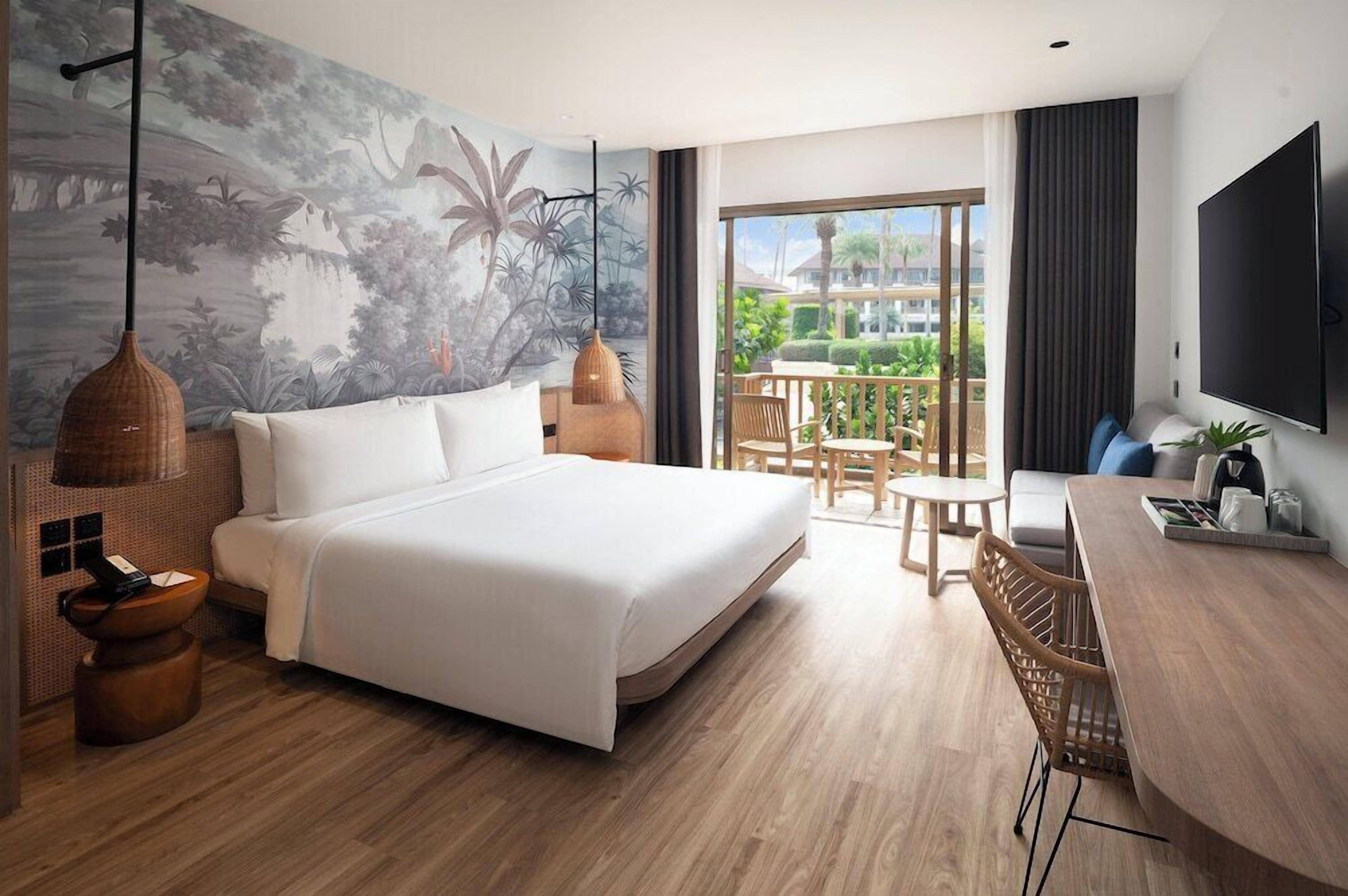 A modern hotel room with a large bed, a dining area, a TV, and a balcony with a view.