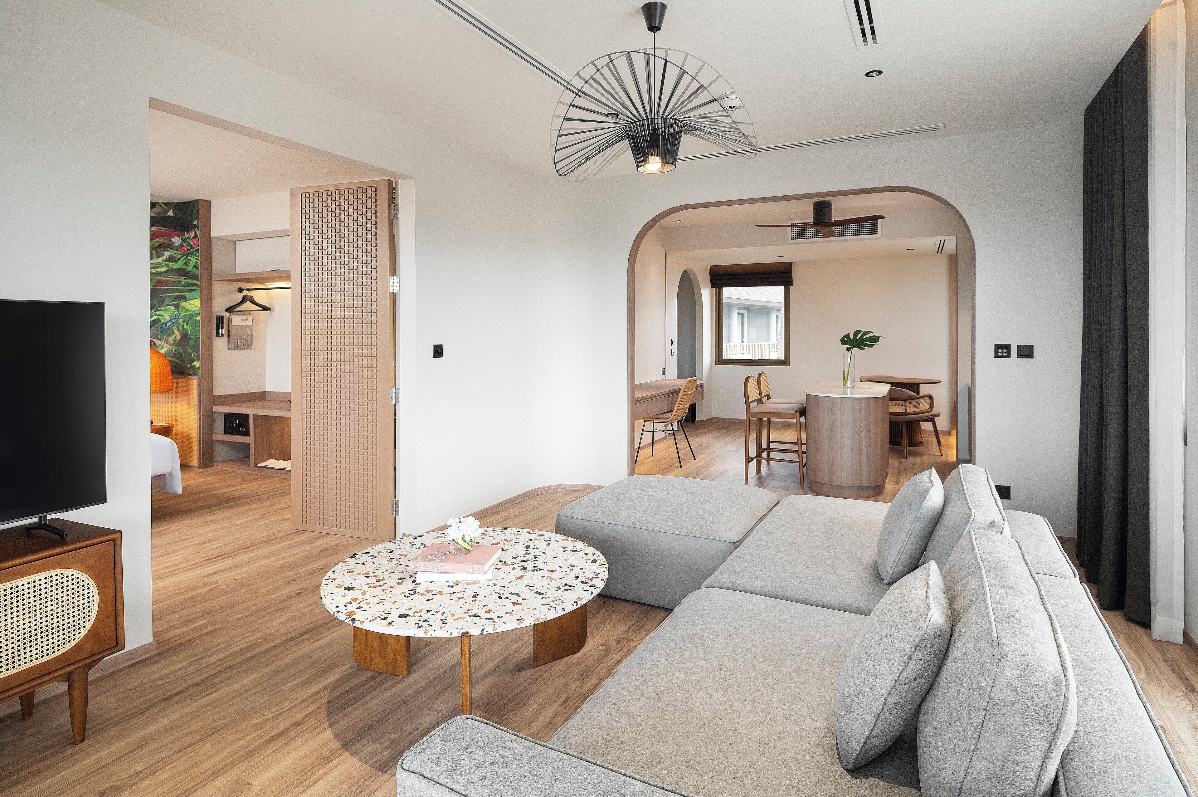 Een moderne woonkamer met een bank, salontafel en televisie. Er is een eethoek met stoelen en een tafel, en een keuken op de achtergrond.