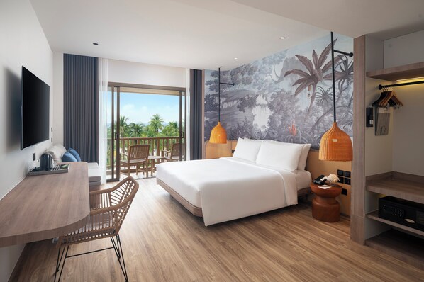 A modern hotel room with a large bed, a desk, a chair, a TV, and a balcony with a view of palm trees. -  Amari Bangsaen (Chonburi)