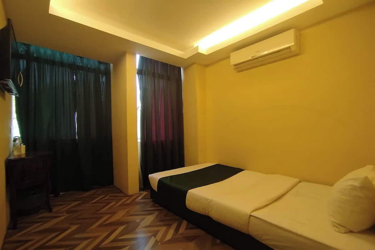 Habitación de hotel con cama, escritorio y unidad de aire acondicionado.