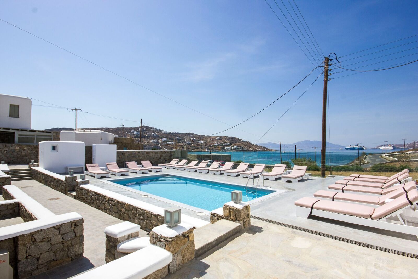 A pool area with lounge chairs and a view of the sea.