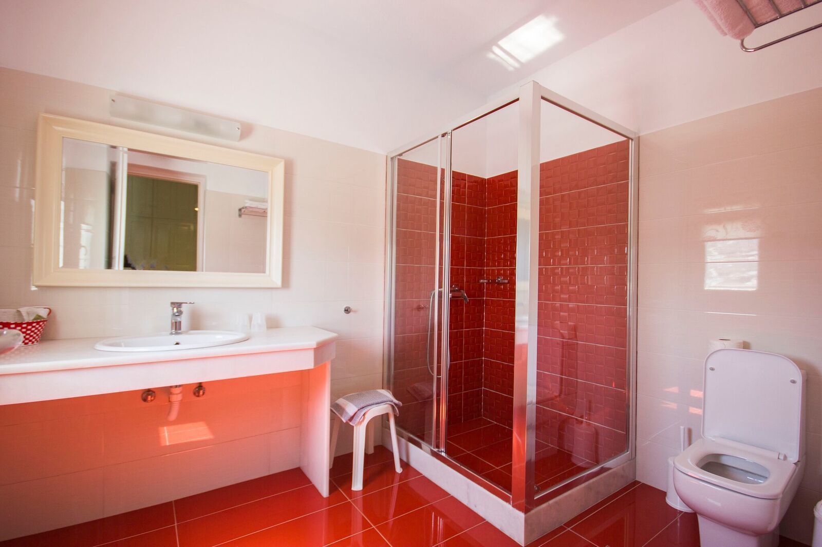 Un baño moderno con cabina de ducha de vidrio, un lavamanos blanco y un inodoro.