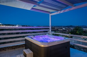 A hot tub on a balcony with a view of a coastal landscape.
