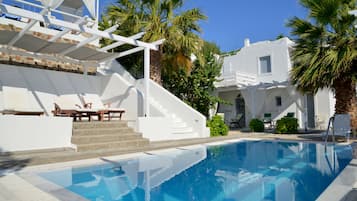 Una piscina al aire libre, sombrillas, sillones reclinables de piscina