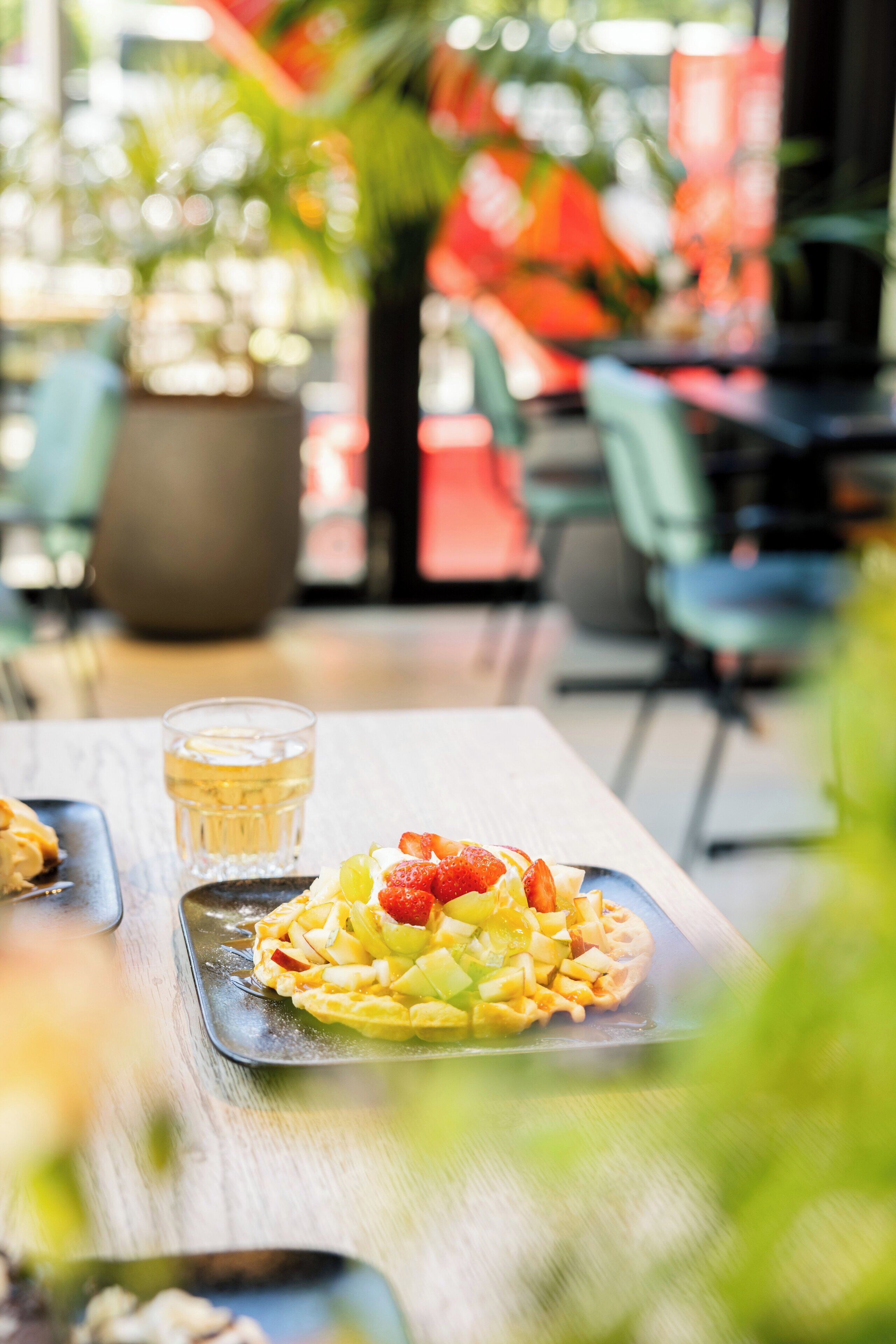 A dining table with a dessert plate and a glass of beverage.
