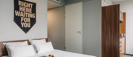 A hotel room with a bed, a wardrobe, and a sign on the wall.