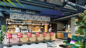 Zona de bar moderna con mostrador, taburetes y un área de estar con sofá y sillones.