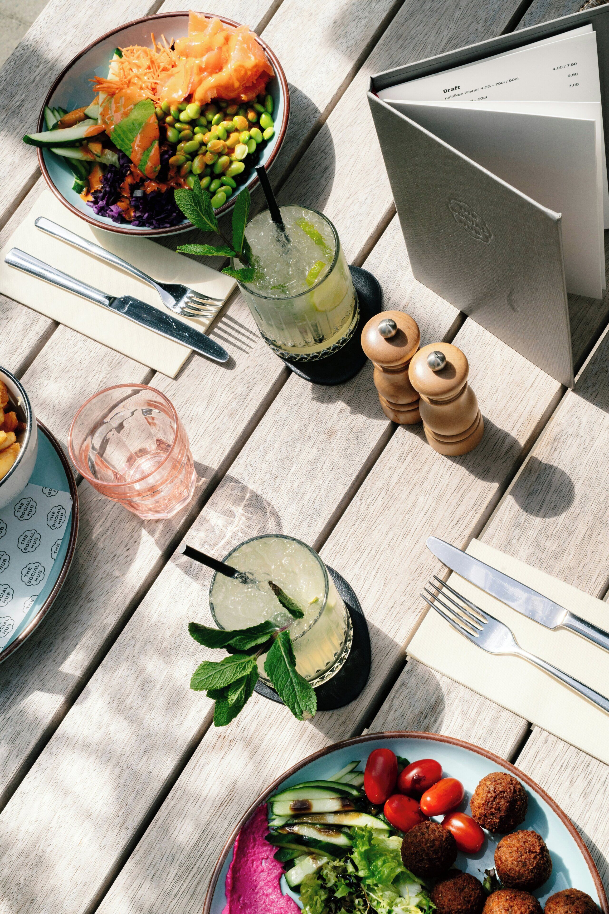 A table with a salad, drinks, and a menu.