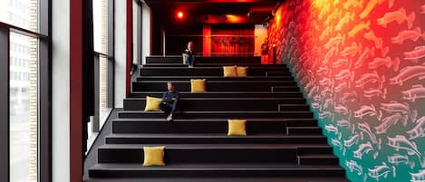 Una escalera con cojines amarillos que lleva a una habitación con un mural de peces rojos y amarillos.