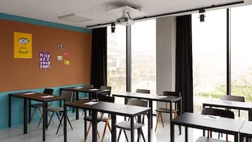 Uma sala de aula com mesas e cadeiras, janelas amplas e cartazes educativos na parede.