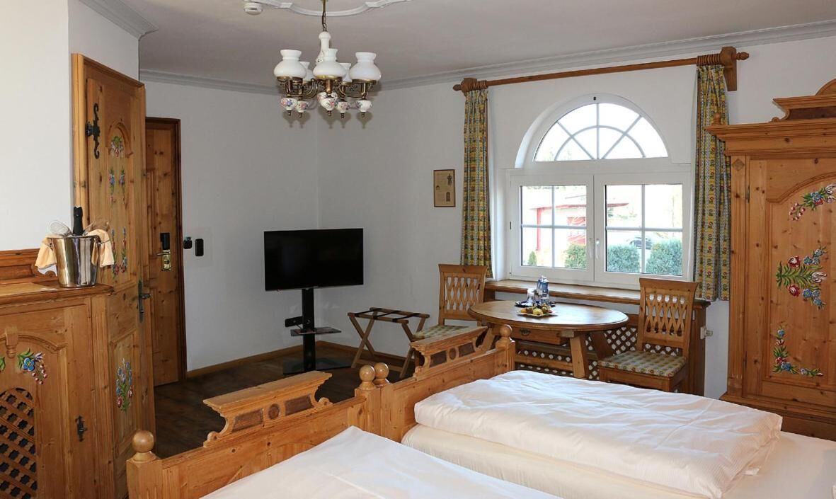 Une pièce comprenant un lit, une télévision, une armoire en bois, une table avec des chaises et une fenêtre avec des rideaux.