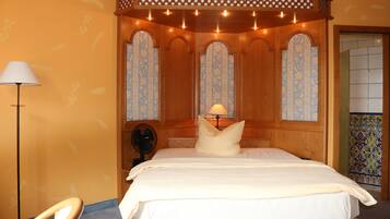 Un dormitorio con cama con dosel, una lámpara de pie y un ventilador.