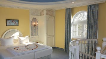 Een slaapkamer met een bed, een kledingkast, een raam met gordijnen en een trap.