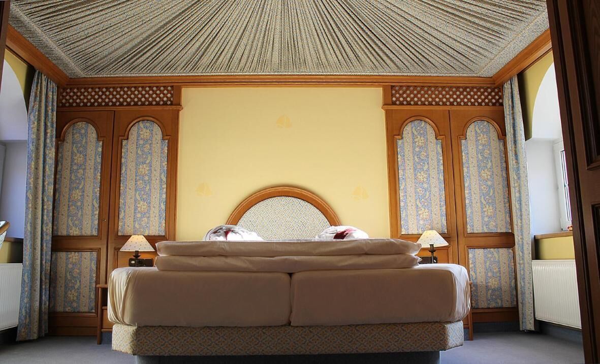 Un dormitorio con una cama grande, dos mesitas de noche y un techo decorativo.