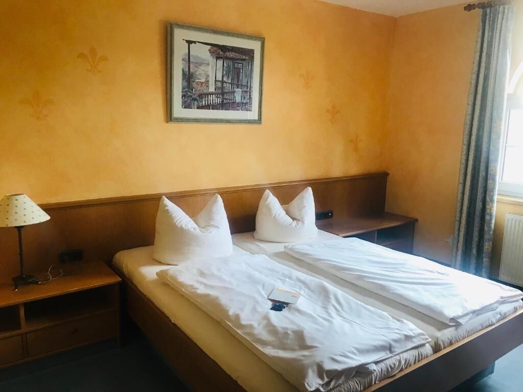 A hotel room with a large bed, a nightstand, a lamp, and a framed picture on the wall.
