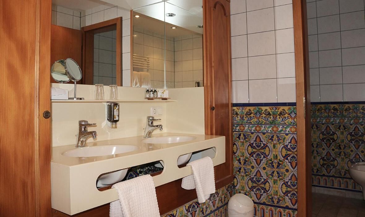 A bathroom with two sinks, a mirror, and a toilet.