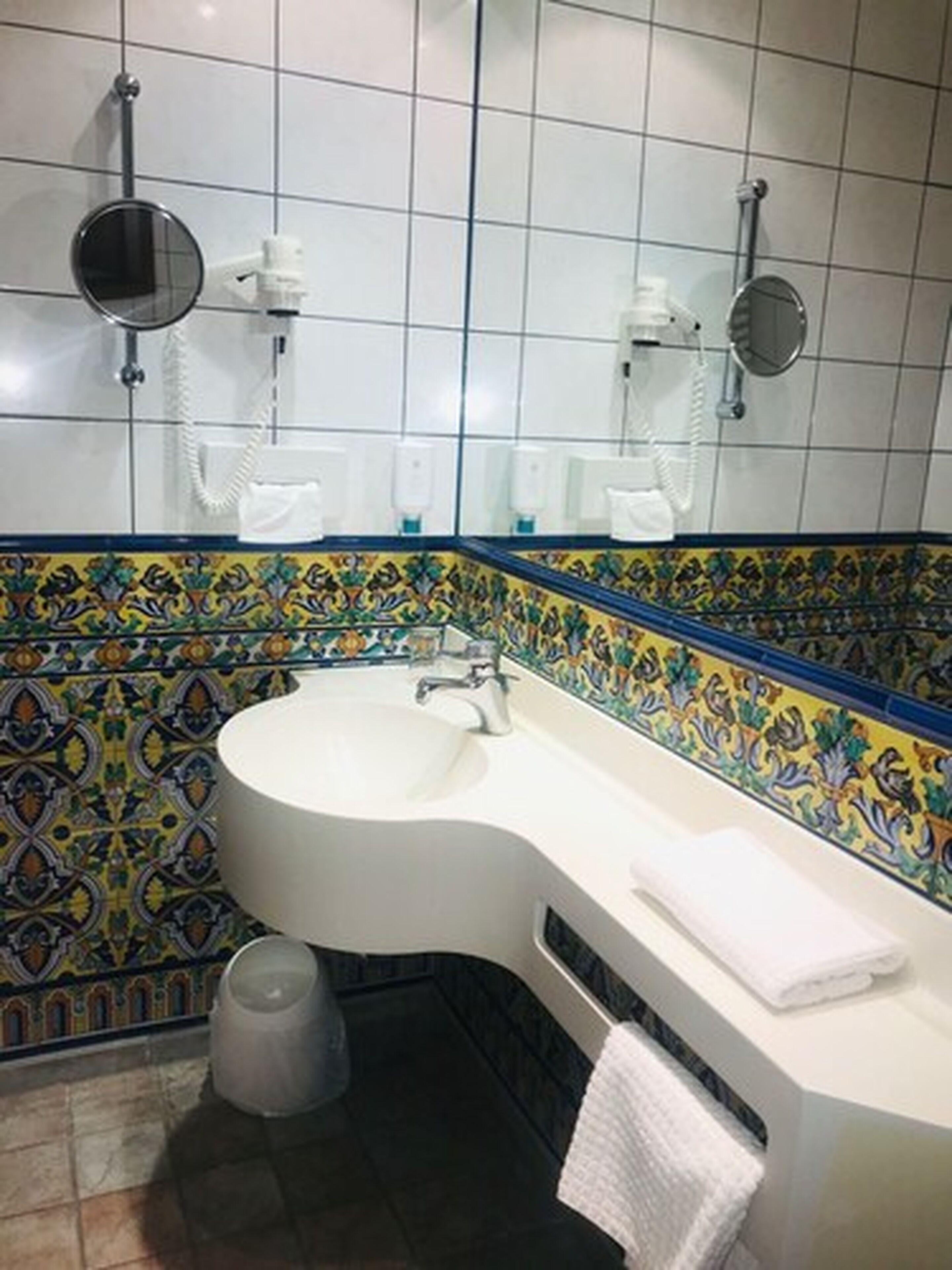 Un bagno con un lavandino bianco, uno specchio e un portasciugamani.