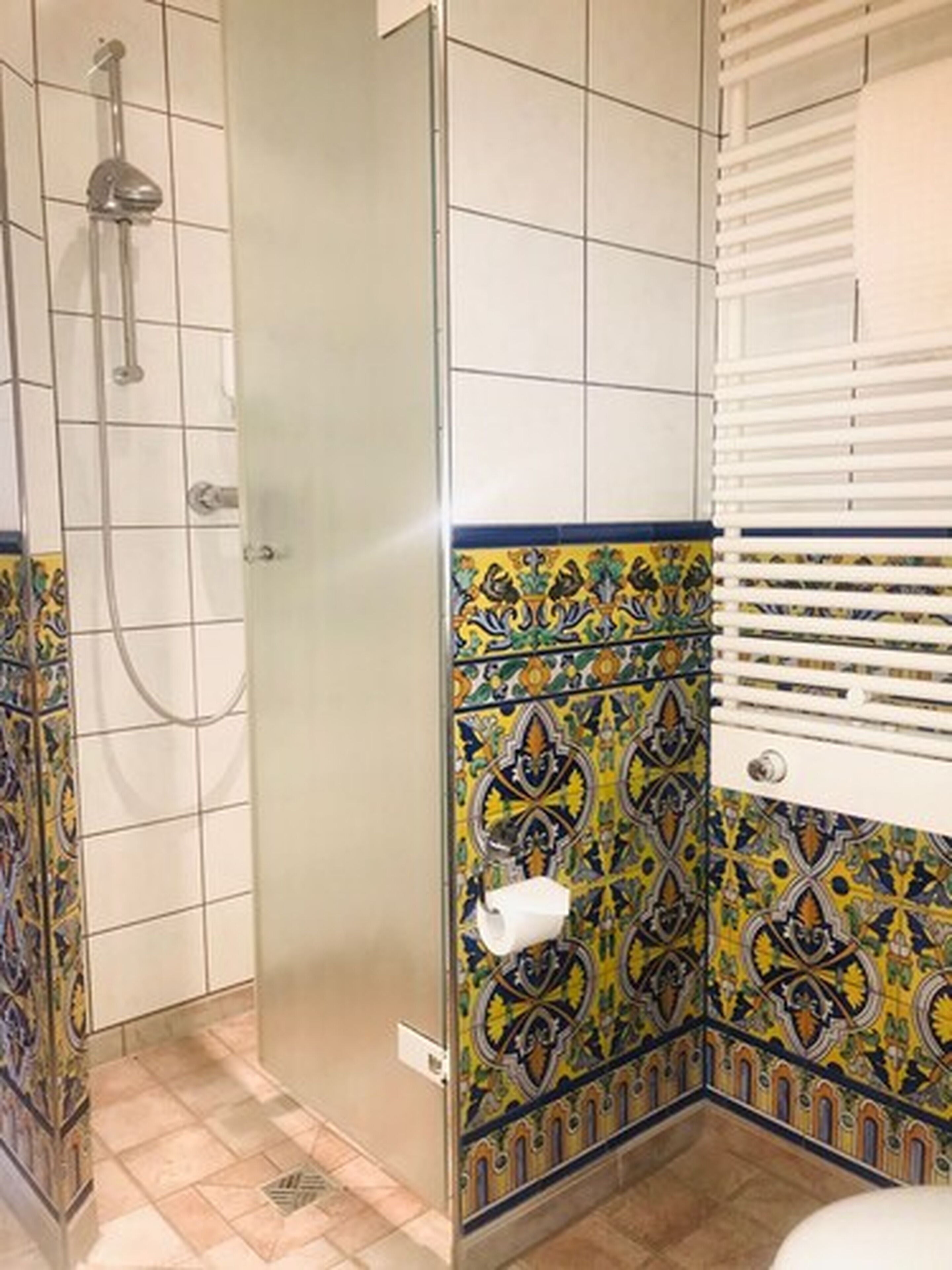 Een badkamer met een douche, betegelde wanden en een toilet.