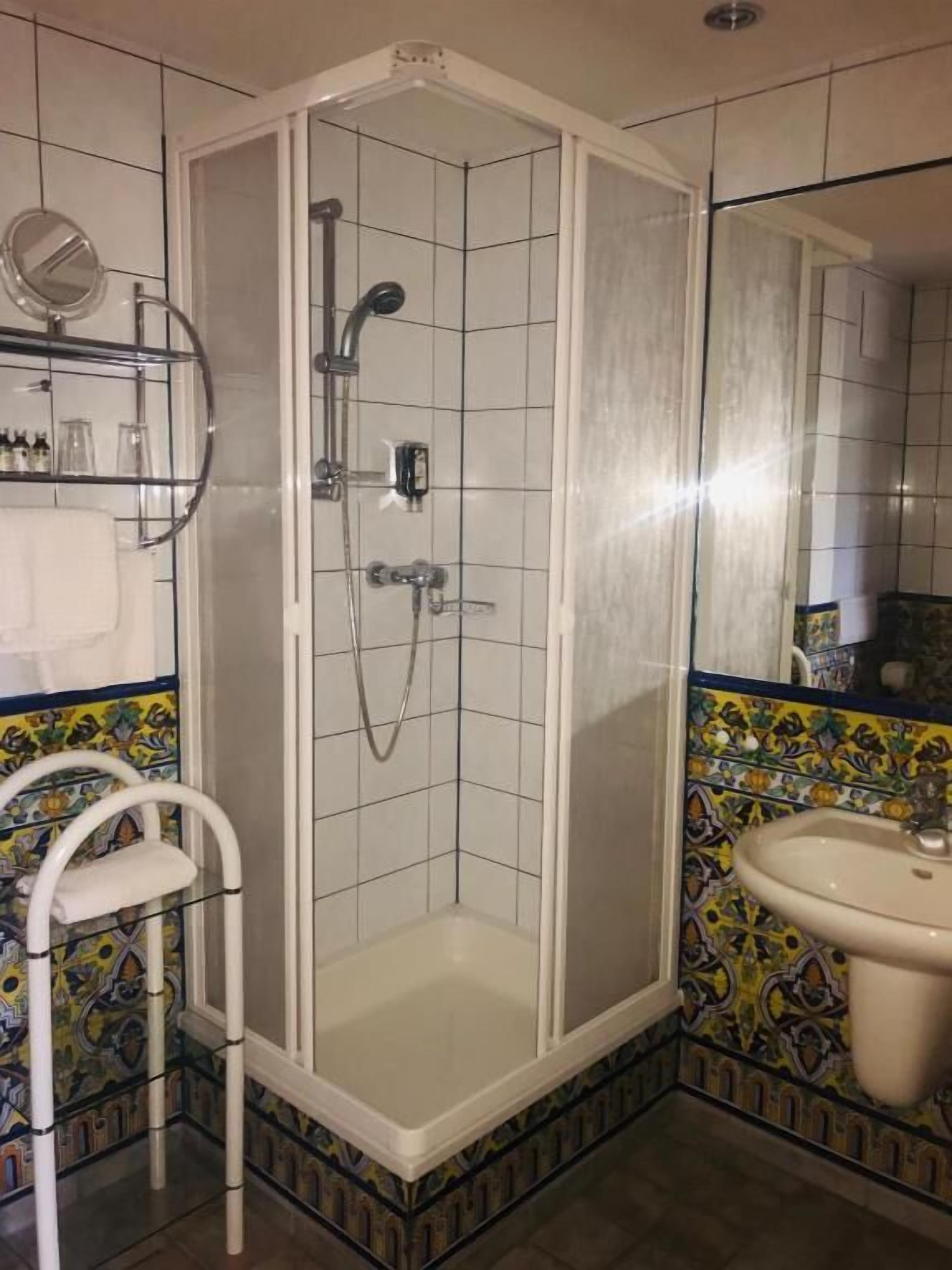 Une salle de bain avec une douche, un lavabo et un miroir.