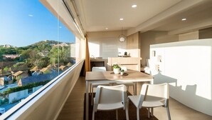Une cuisine moderne avec un coin repas, de grandes fenêtres et une vue sur une colline.