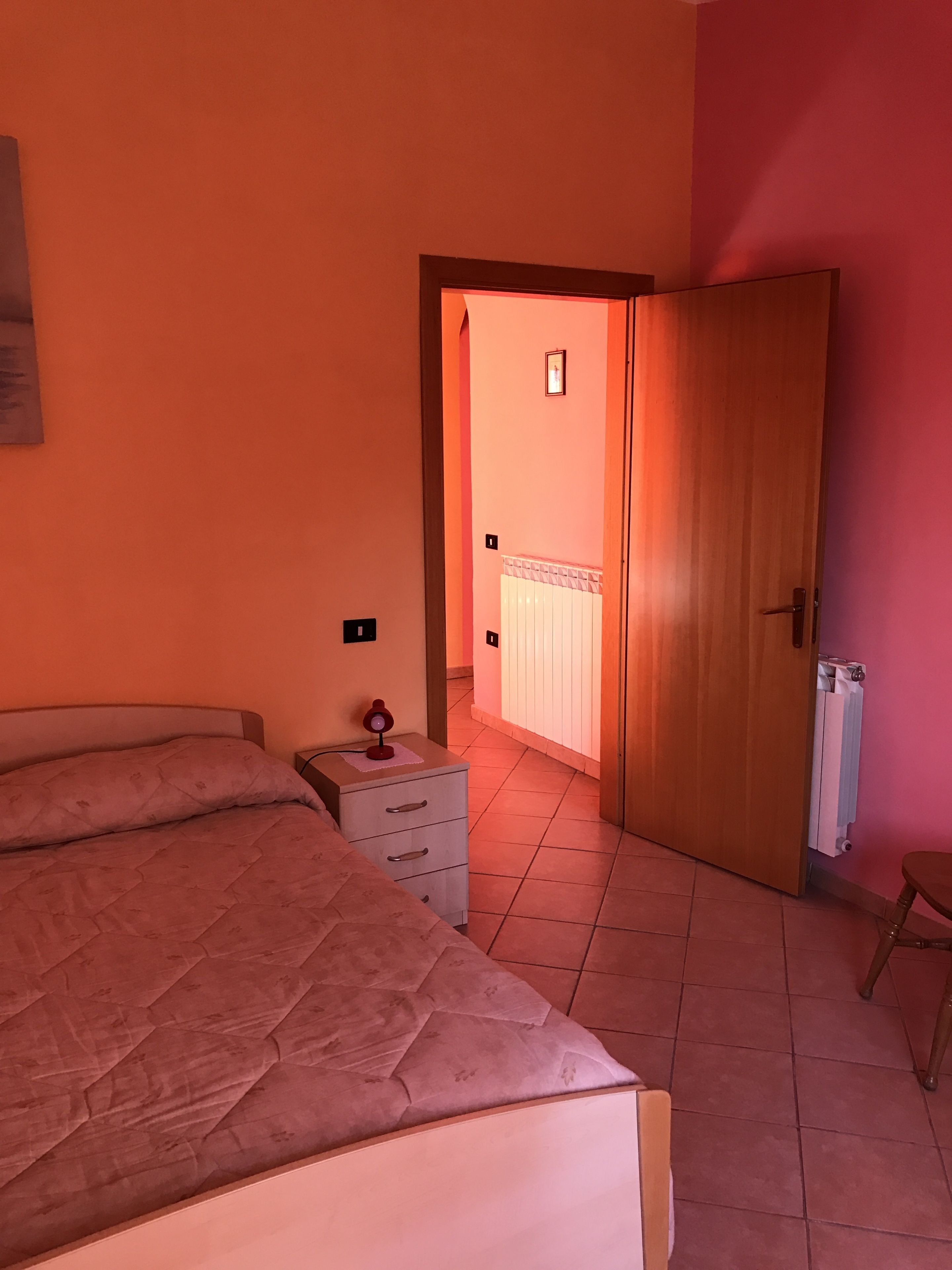 Une chambre à coucher comprenant un lit, une table de chevet, une commode et une porte donnant sur une autre pièce.