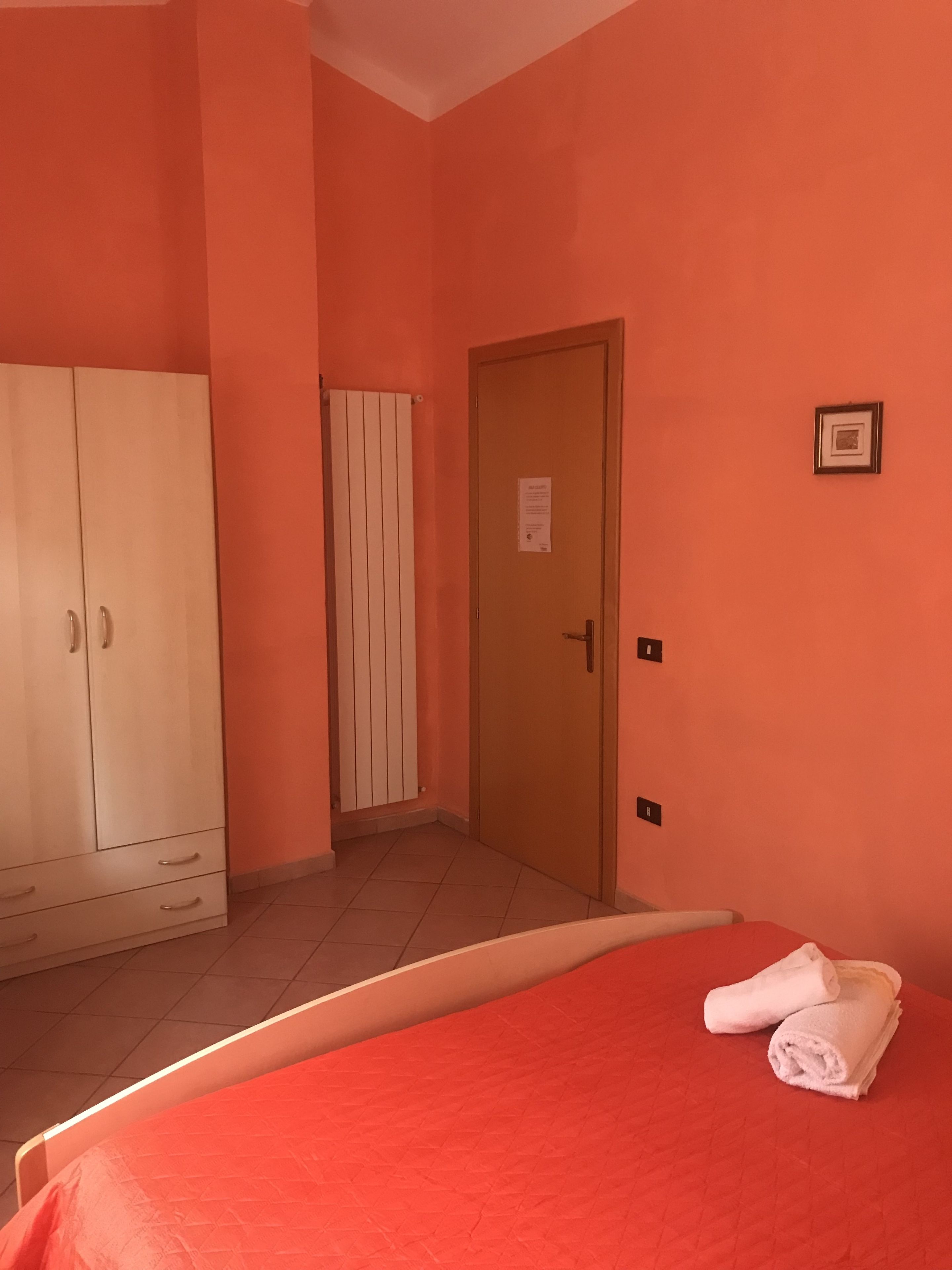 Habitación de hotel con cama, armario, puerta y radiador.