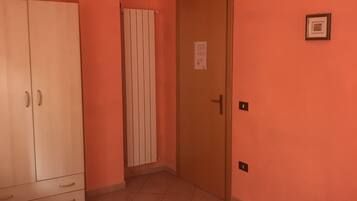 Habitación de hotel con cama, armario, puerta y radiador.