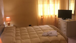 A bedroom with a bed, a desk with a computer, an air conditioner, and a window with curtains. - Bed & Breakfast Cilento (San Mauro Cilento)