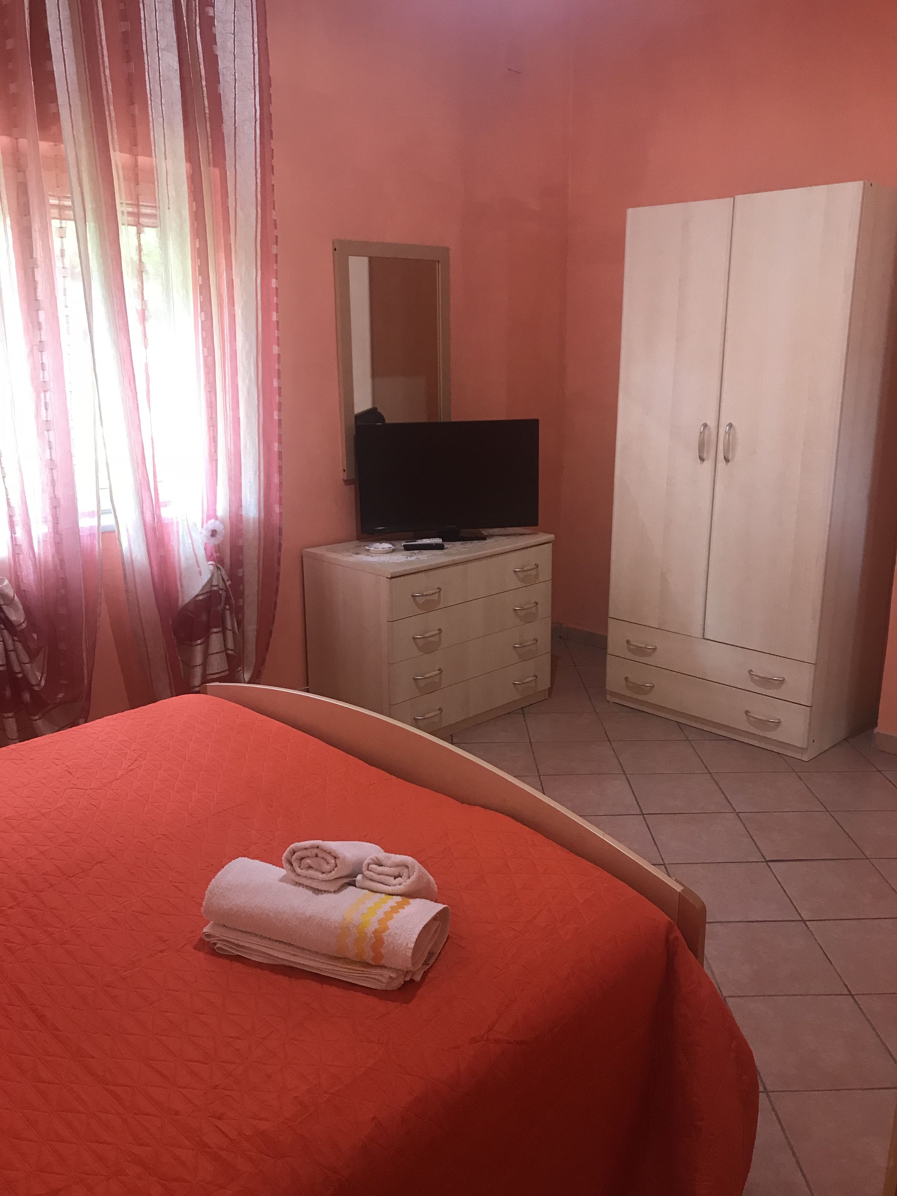 Een hotelkamer met een bed, een dressoir, een televisie en een kledingkast.